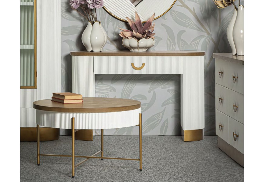 Designová glamour sestava bílého obývacího nábytku s oblými tvary a ozdobným svislým drážkováním s detaily v metalické bronzové barvě s vrchními deskami v naturální světlé hnědé barvě dřeva